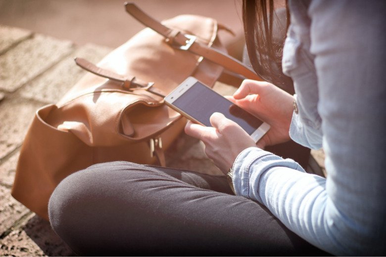 A person is sitting and looking at her phone