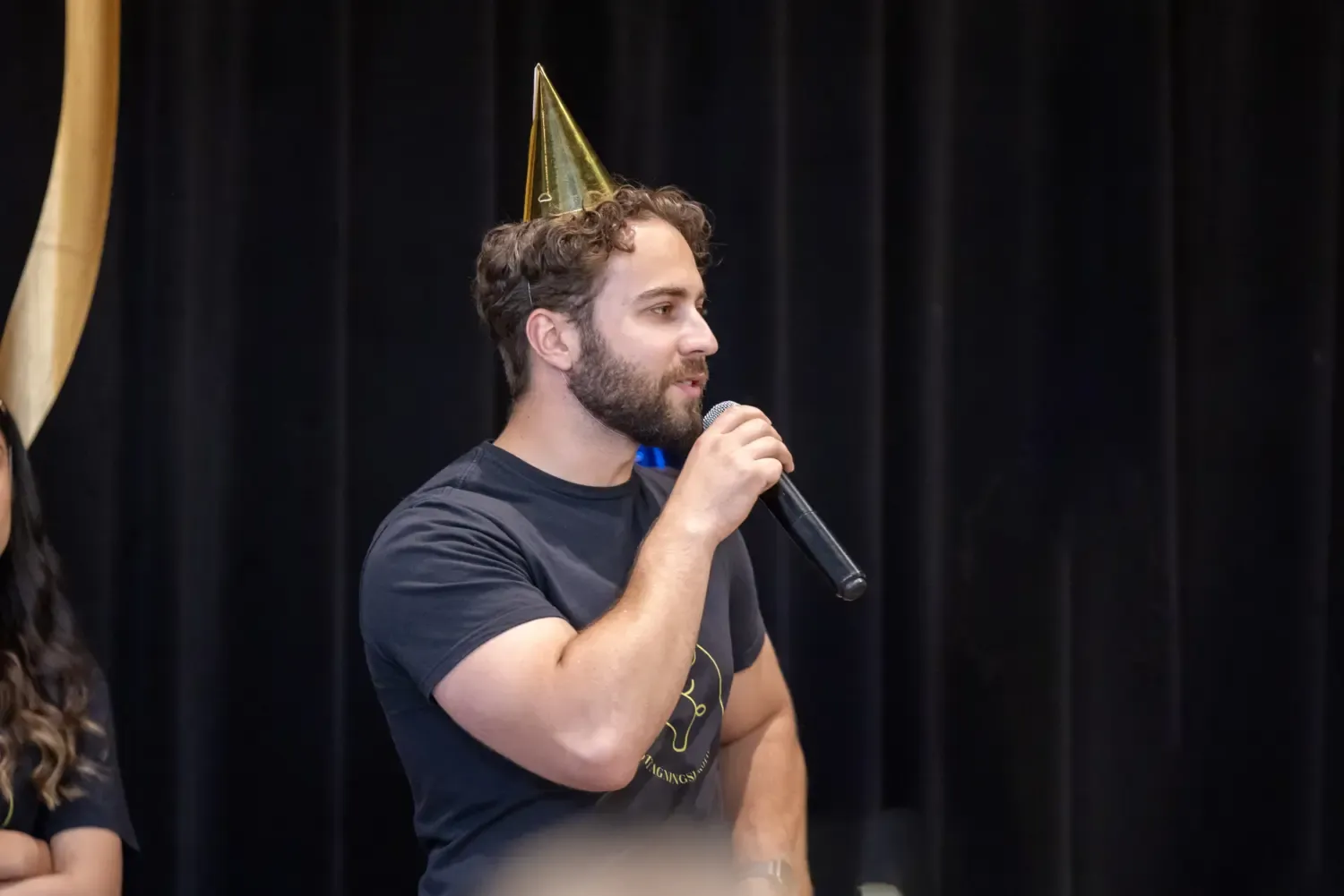 KI student Artem is standing on a stage, talking in to a microphone.