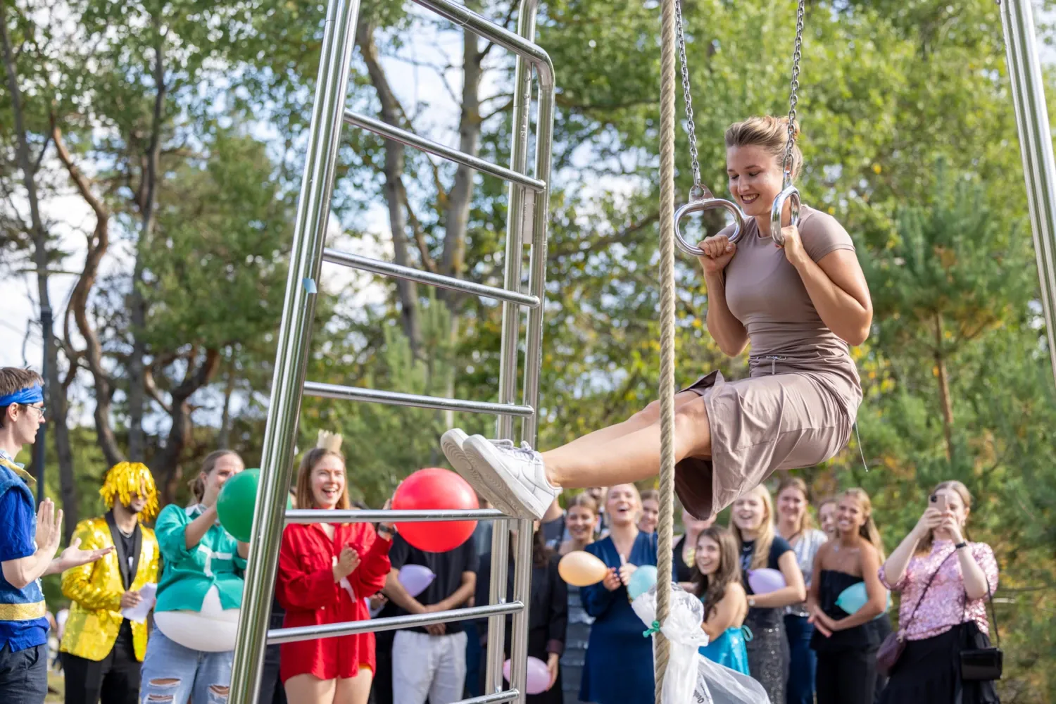 Student hanging in gym rings at the outdoor gym on campus