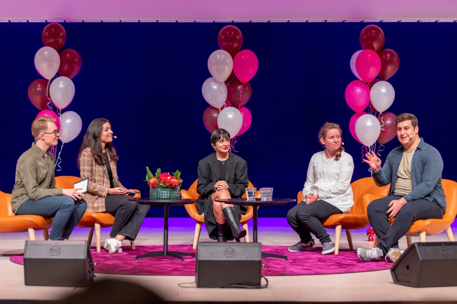 Five students sitting in chairs talking.