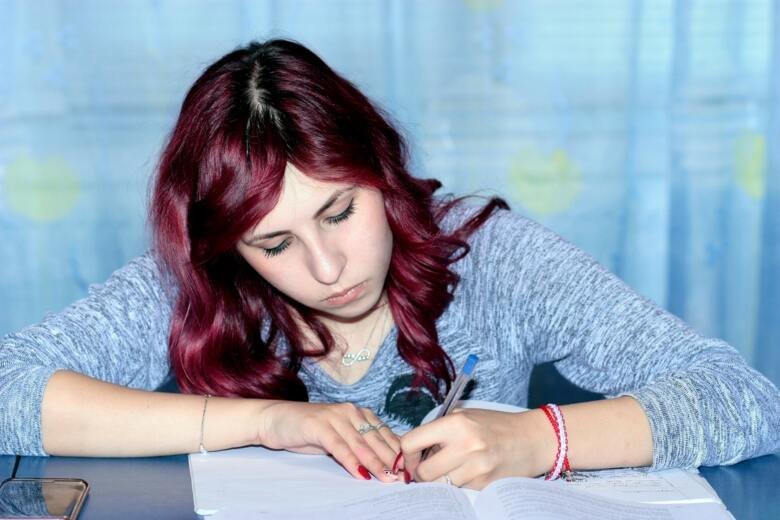 Red-haired female student studying and writing