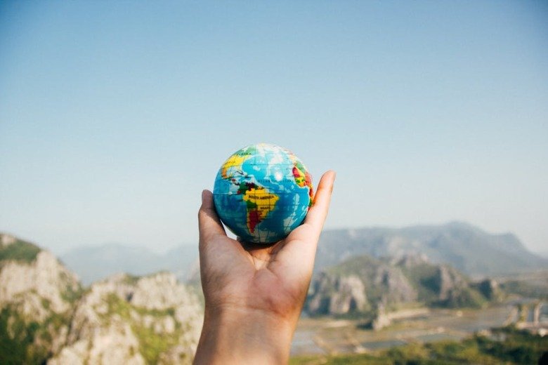 A hand holding up a small globe.