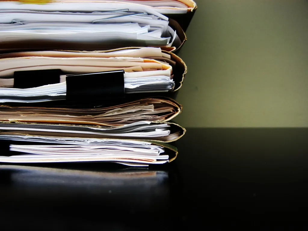 Stack of papers in folders on a table.
