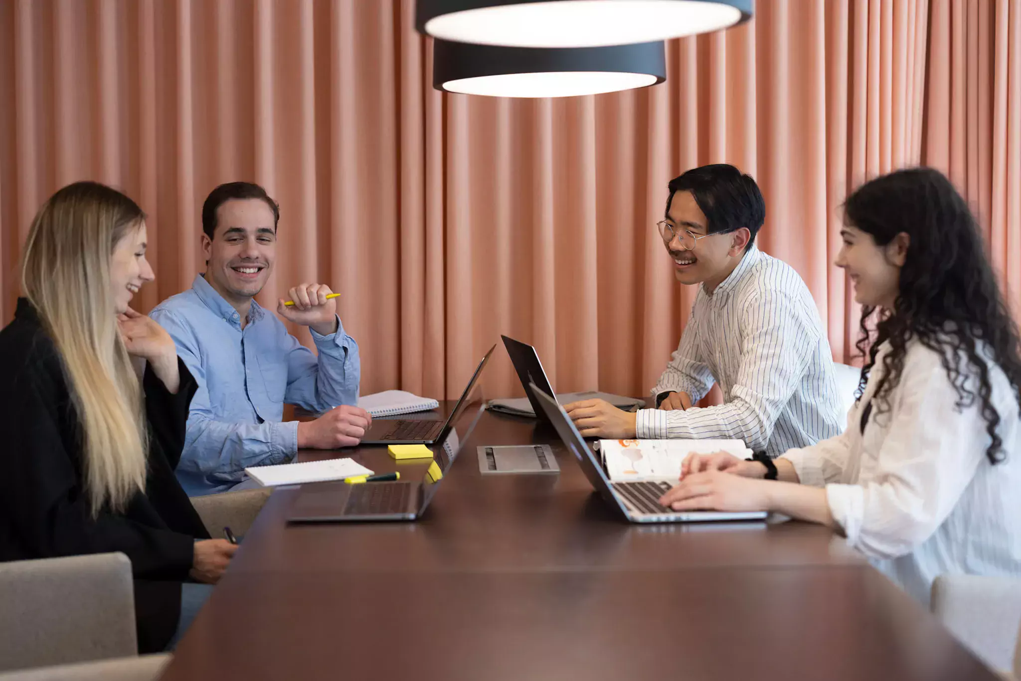 Four students by a table studying, laughing and talking.